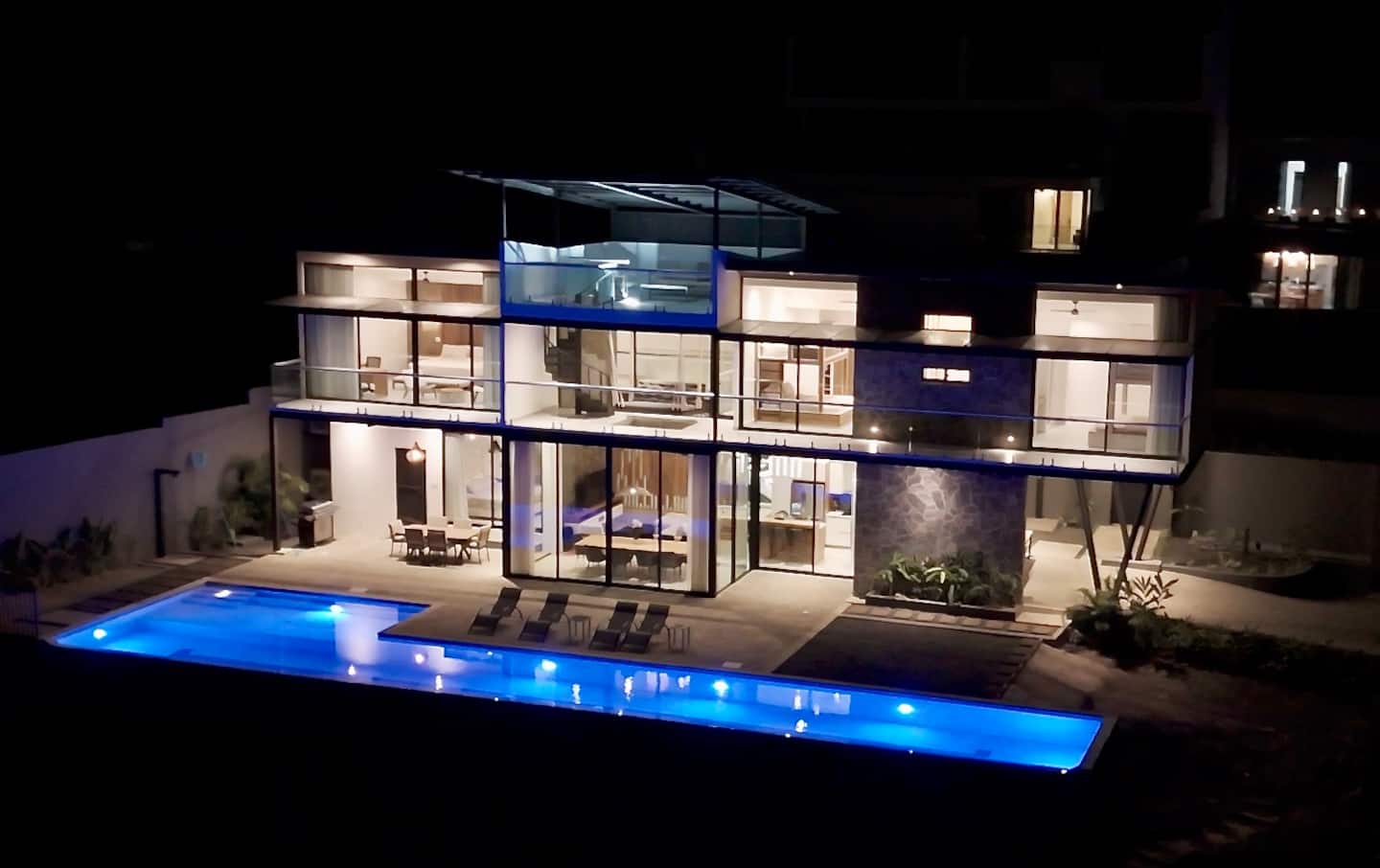 The house lit up at night with the pool glowing blue
